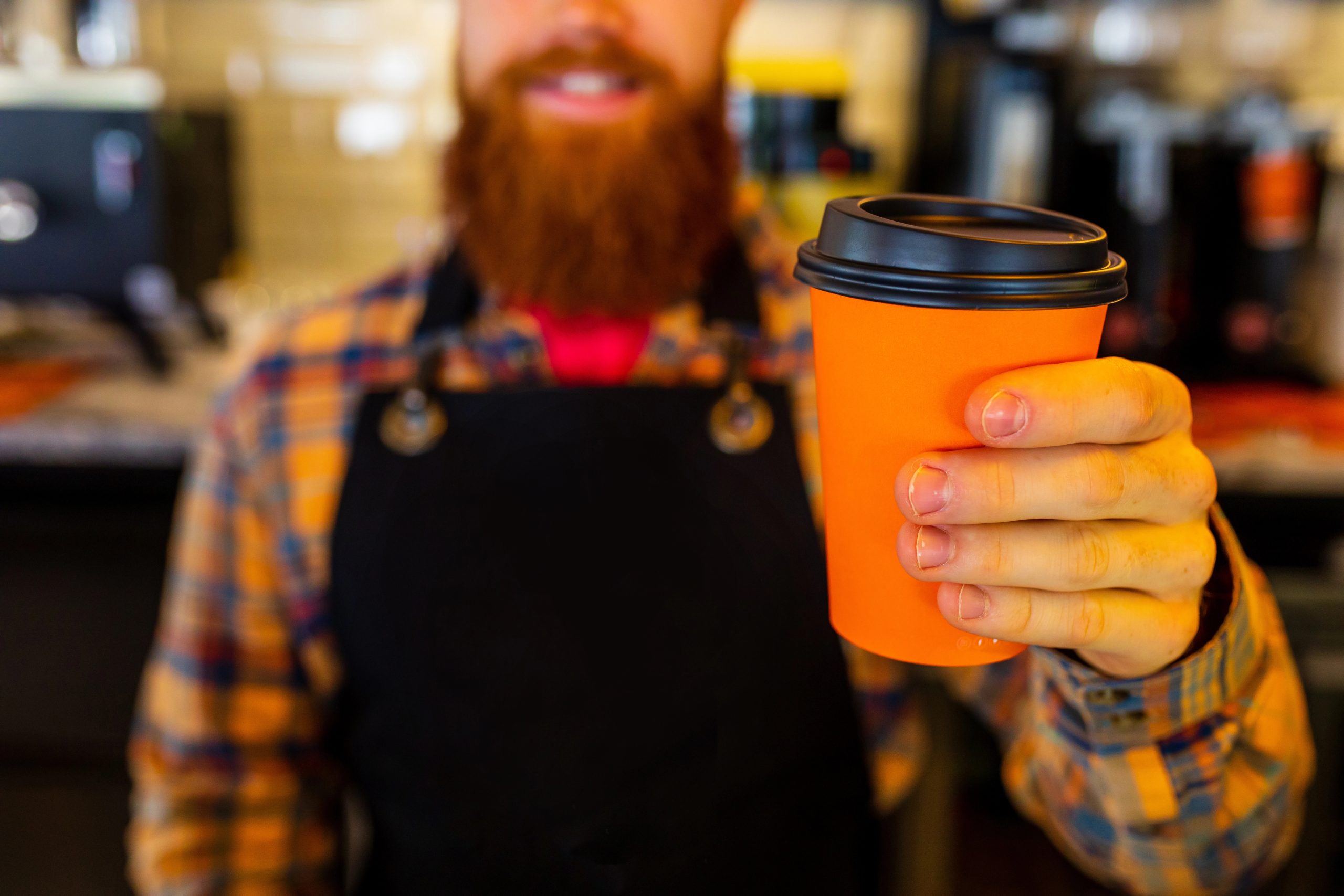 to_go_coffee_order male barrista handing coffee toward camera